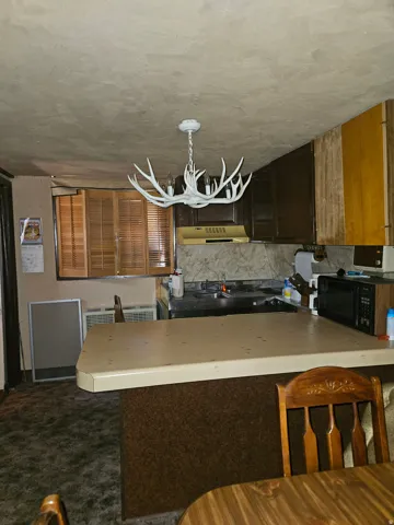 Kitchen with a breakfast bar, built-in cabinetry, and a window with wood blinds