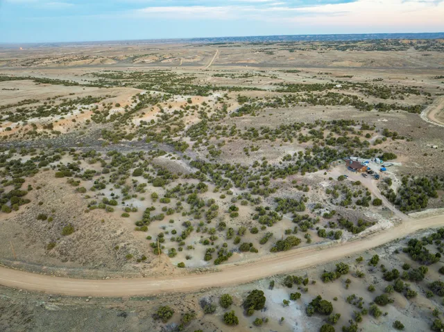Expansive land parcel featuring natural shrubbery and a single-story structure with a brown roof