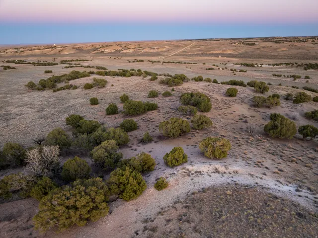 Expansive land parcel featuring natural shrubbery, varied topography, and distant open horizons