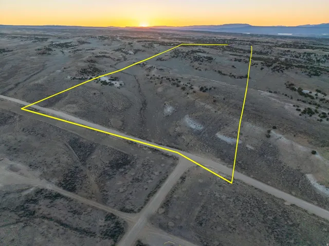 Expansive undeveloped acreage featuring a defined property boundary, natural terrain, and direct road frontage