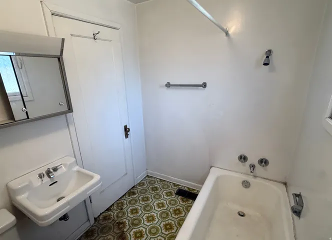 Bathroom featuring a wall-mounted sink, medicine cabinet with mirrored door, and patterned floor tile