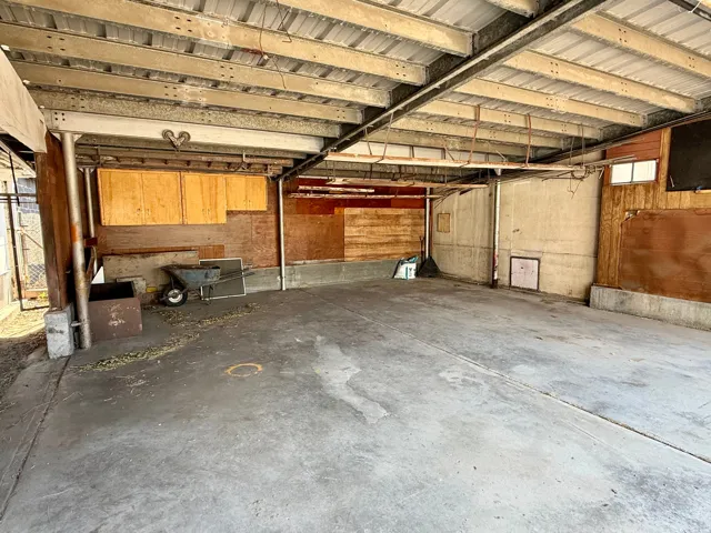 Open-air structure featuring a concrete floor, exposed metal beam ceiling, and mixed-material walls