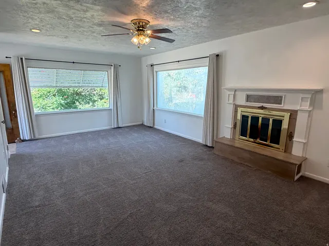 Spacious living area featuring a fireplace with a white mantel and brass-accented doors