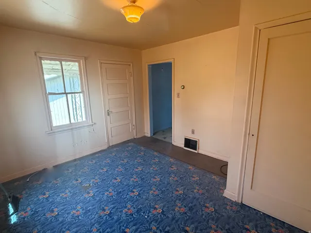 Room with a window, paneled interior door, and a flush-mounted ceiling light fixture