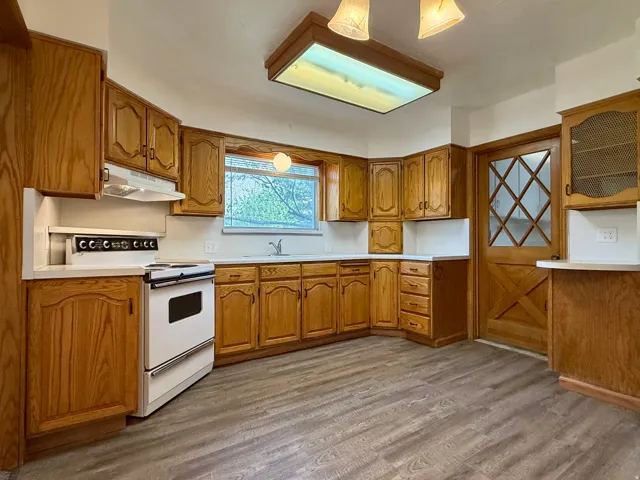 Kitchen featuring wood-finish cabinetry, white countertops, and wood-finish flooring