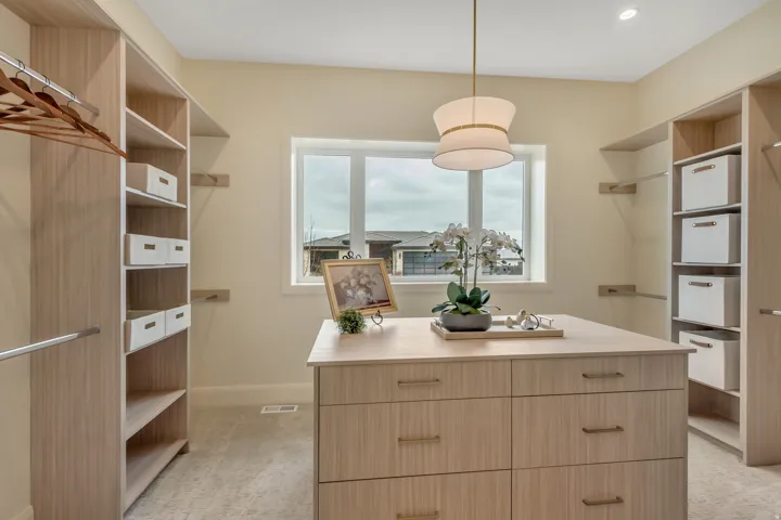 Spacious closet featuring custom built-in cabinetry, a central island with integrated drawers, and a window for natural light