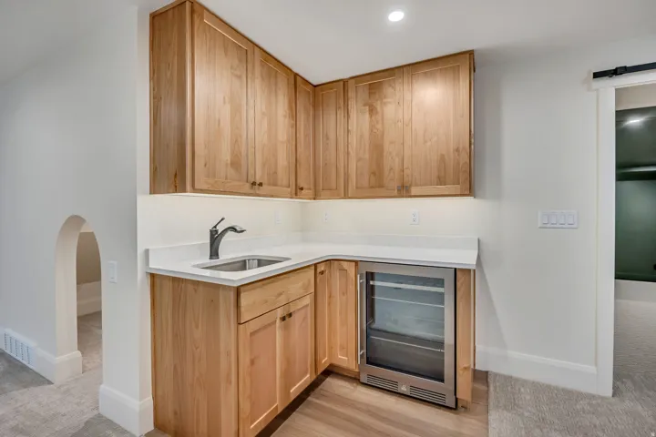 Wet bar featuring an undermount sink, under-cabinet lighting, and a built-in beverage refrigerator