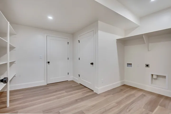 Dedicated laundry area with utility hookups and integrated shelving, cold storage room door