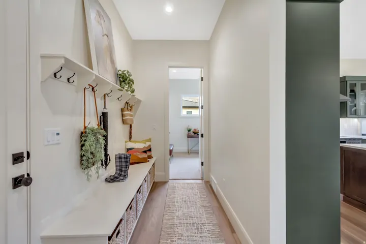 Entryway featuring built-in bench seating with wall-mounted coat hooks, a great transition from garage to kitchen