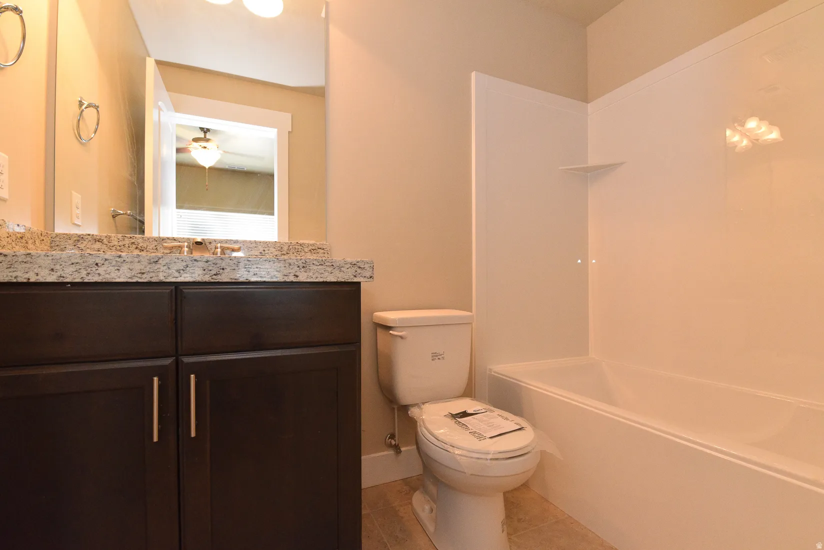Bathroom featuring a dark wood vanity with a light speckled countertop, undermount sink, and chrome faucet