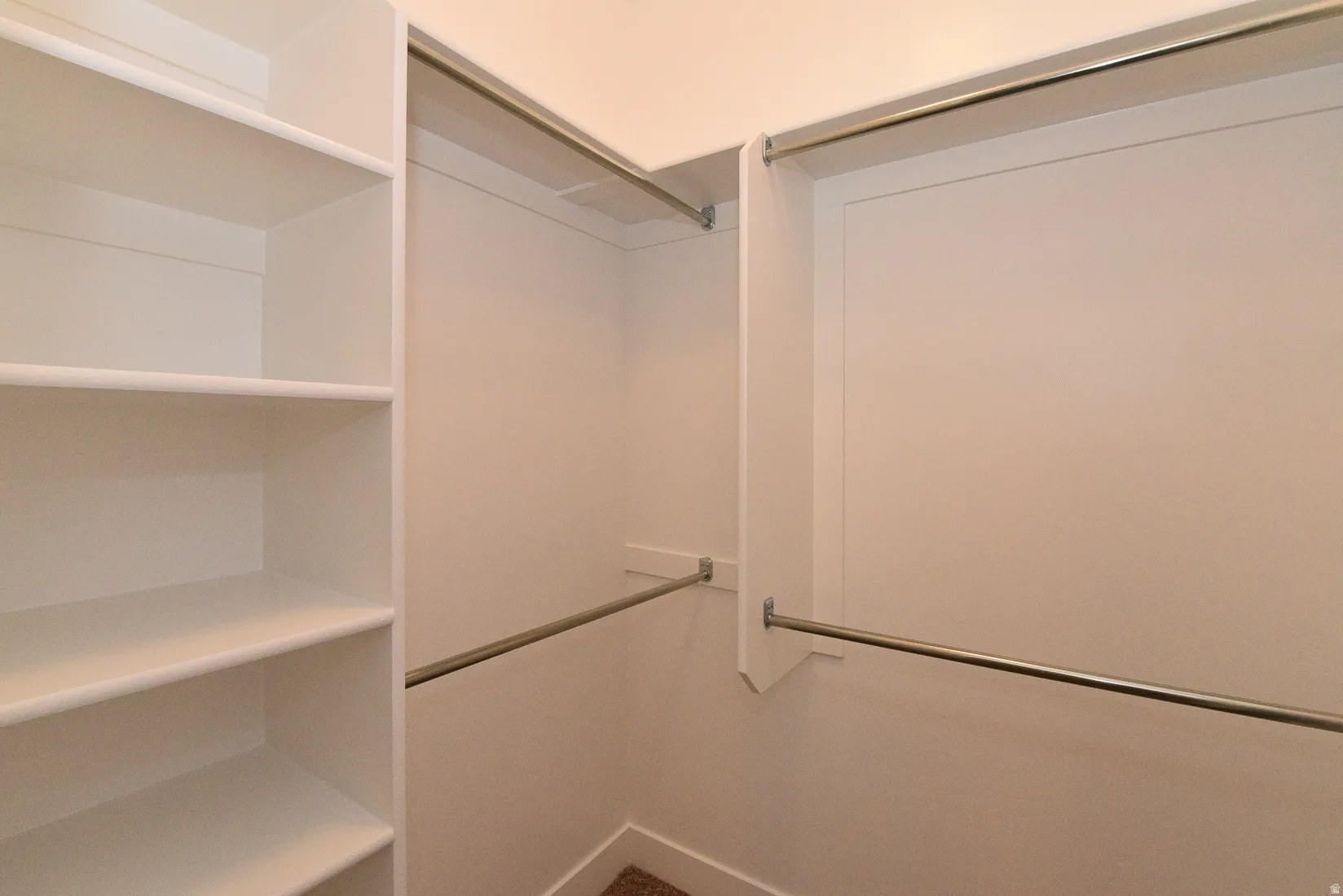 Walk-in closet with built-in shelving, multiple hanging rods, and neutral wall tones