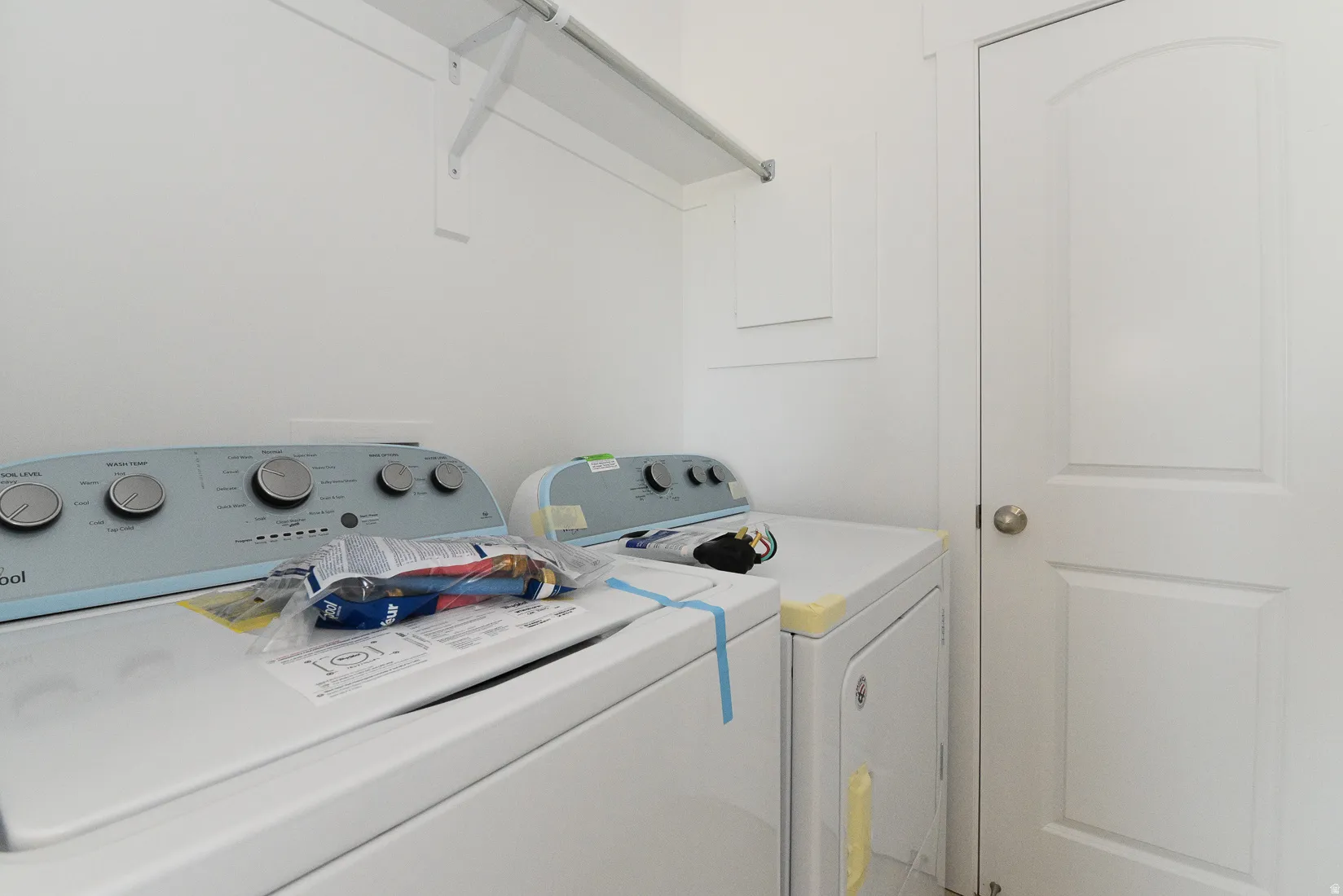 Dedicated laundry area featuring white walls, a white arch-panel door, and a built-in white wire shelving unit
