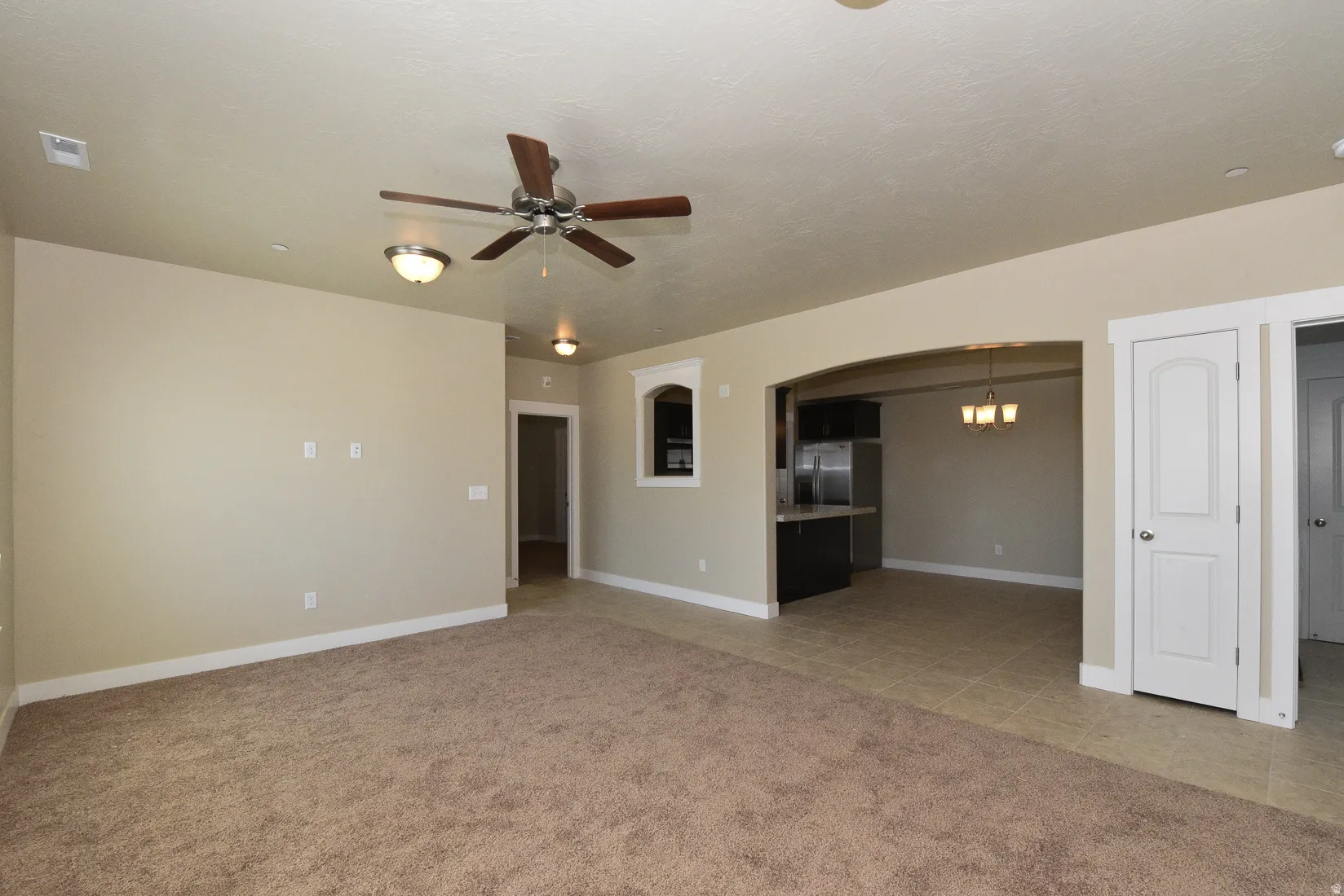 Spacious room featuring neutral carpeting, a ceiling fan with light fixture, and recessed lighting