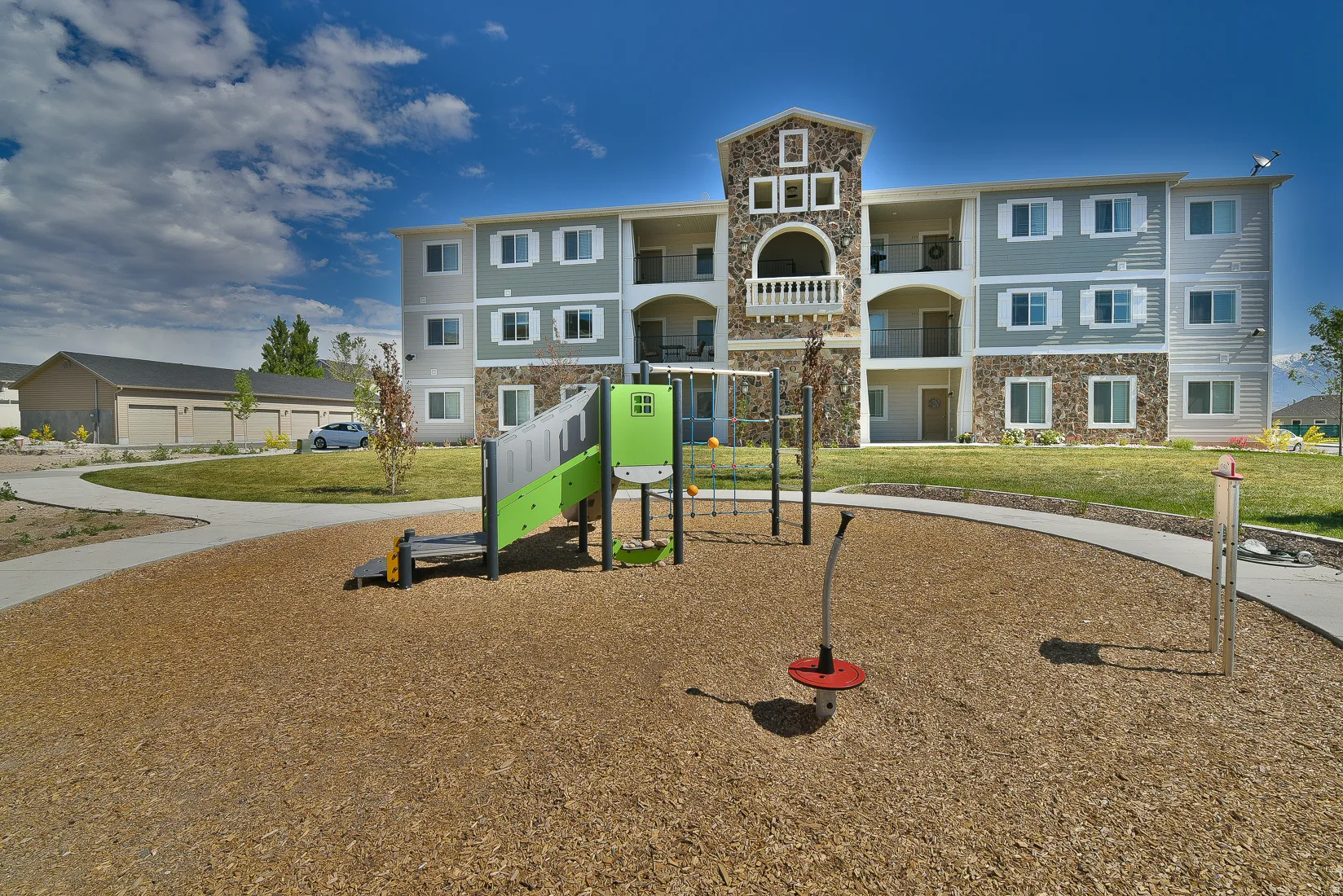 Multi-story building featuring a stone and siding exterior with balconies and ground-level patios