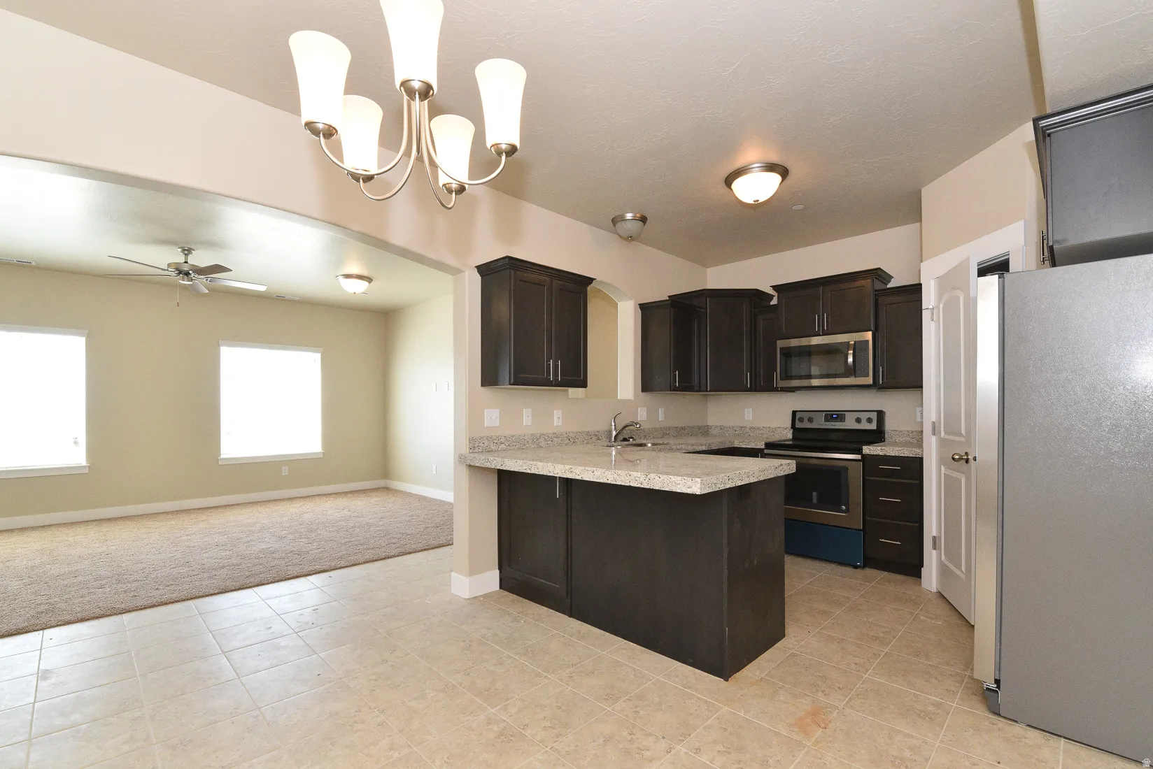 Kitchen featuring dark wood-finish cabinetry, light-toned countertops, and stainless steel appliances