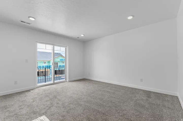 Spacious room featuring neutral carpeting, white walls, and recessed lighting