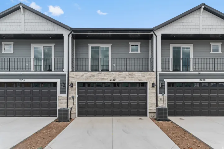 Modern exterior featuring dark gray siding, light stone veneer accents, and black trim