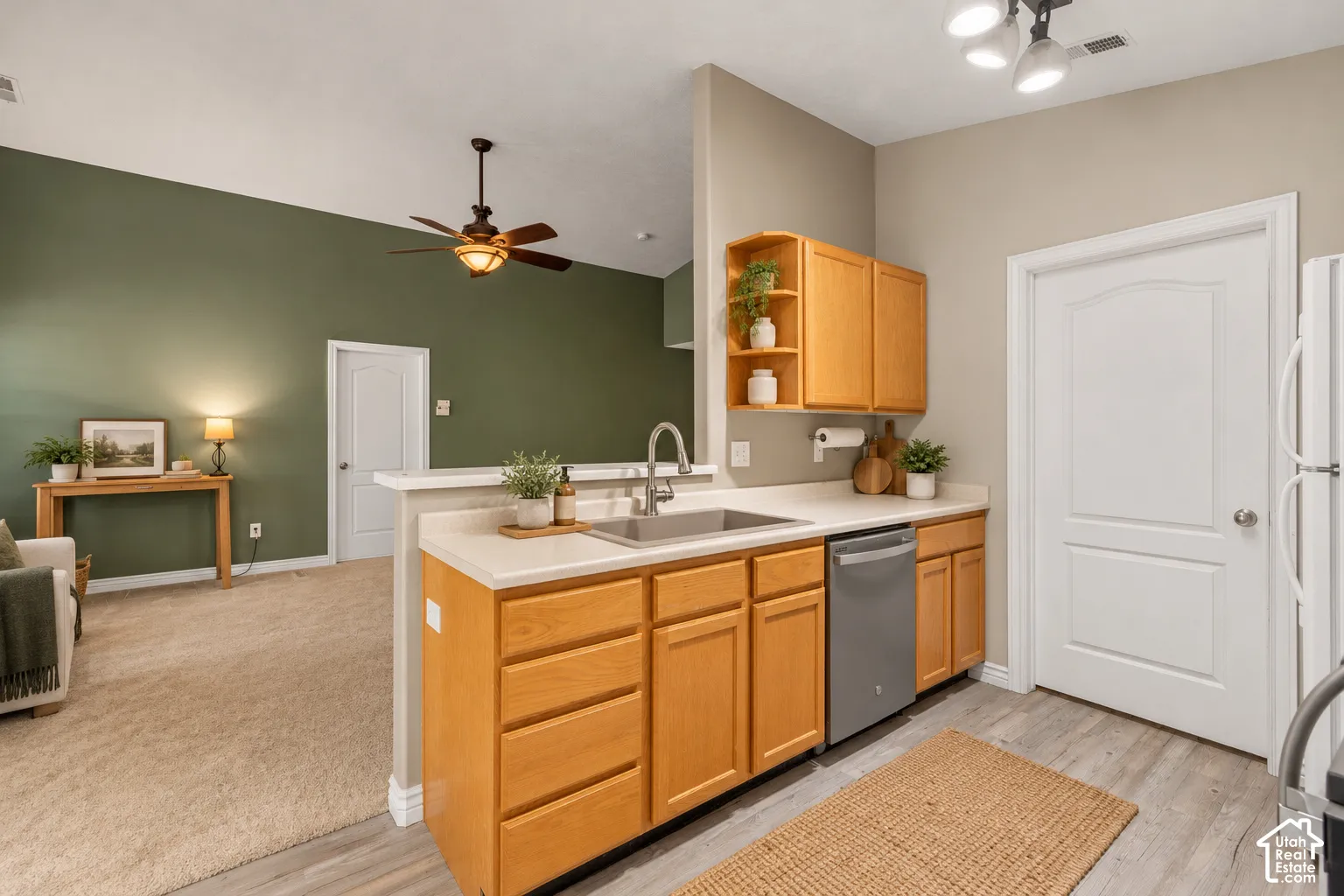 Kitchen featuring wood cabinetry with built-in open shelving, stainless steel sink with a high-arch faucet, wood-finish flooring, and a ceiling-mounted light fixture. Virtually Staged.