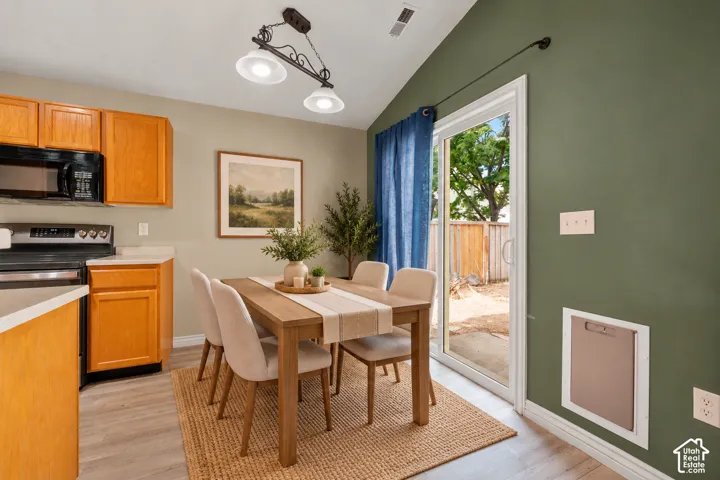 Vaulted ceilings, sliding glass door, wooden cabinetry, built-in wall-mounted pet door, and pendant lighting. Virtually Staged.