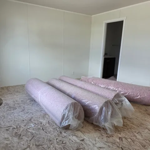 Room featuring light-toned panel walls and visible subflooring, indicating a new flooring installation
