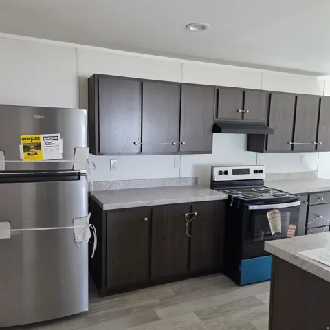 Kitchen featuring dark wood-finish cabinetry, light-toned countertops, and wood-finish flooring