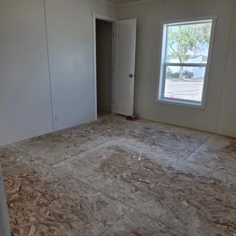 Room featuring unfinished subflooring, white painted walls, and a single-pane window with white trim
