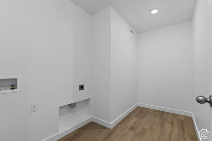 Dedicated utility space with wood-finish flooring, recessed ceiling lighting, and crisp white walls