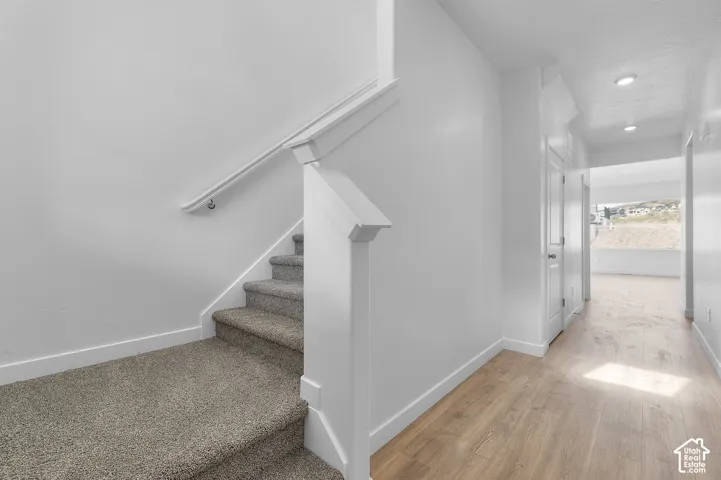 Carpeted staircase with white handrail and newel post