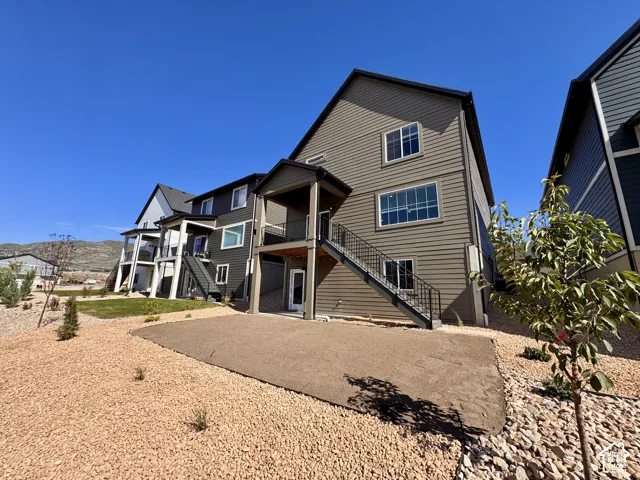 Multi-level exterior featuring horizontal siding, multiple balconies, and an outdoor staircase with wrought iron railings