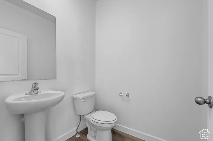 Bathroom featuring a pedestal sink, wall-mounted mirror, and wood-finish flooring