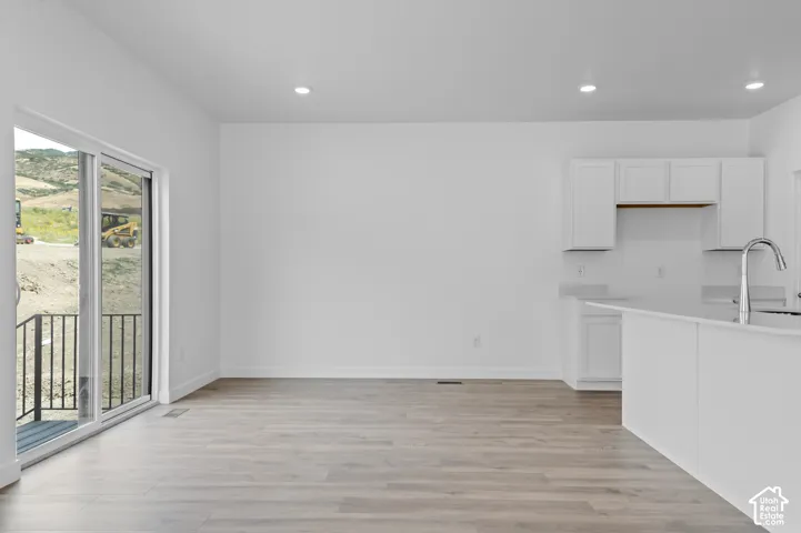 Bright open-concept living area featuring wood-finish flooring, recessed lighting, and a white color palette