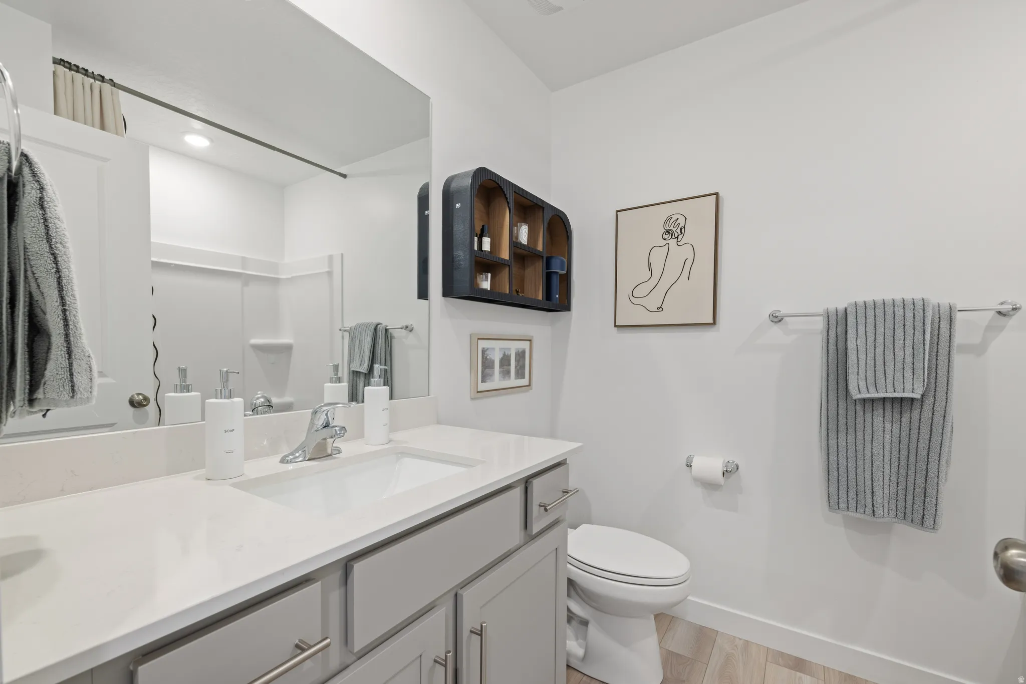 Upstairs hallway bathroom vanity featuring a single sink, light gray cabinetry with brushed nickel hardware, and a white countertop