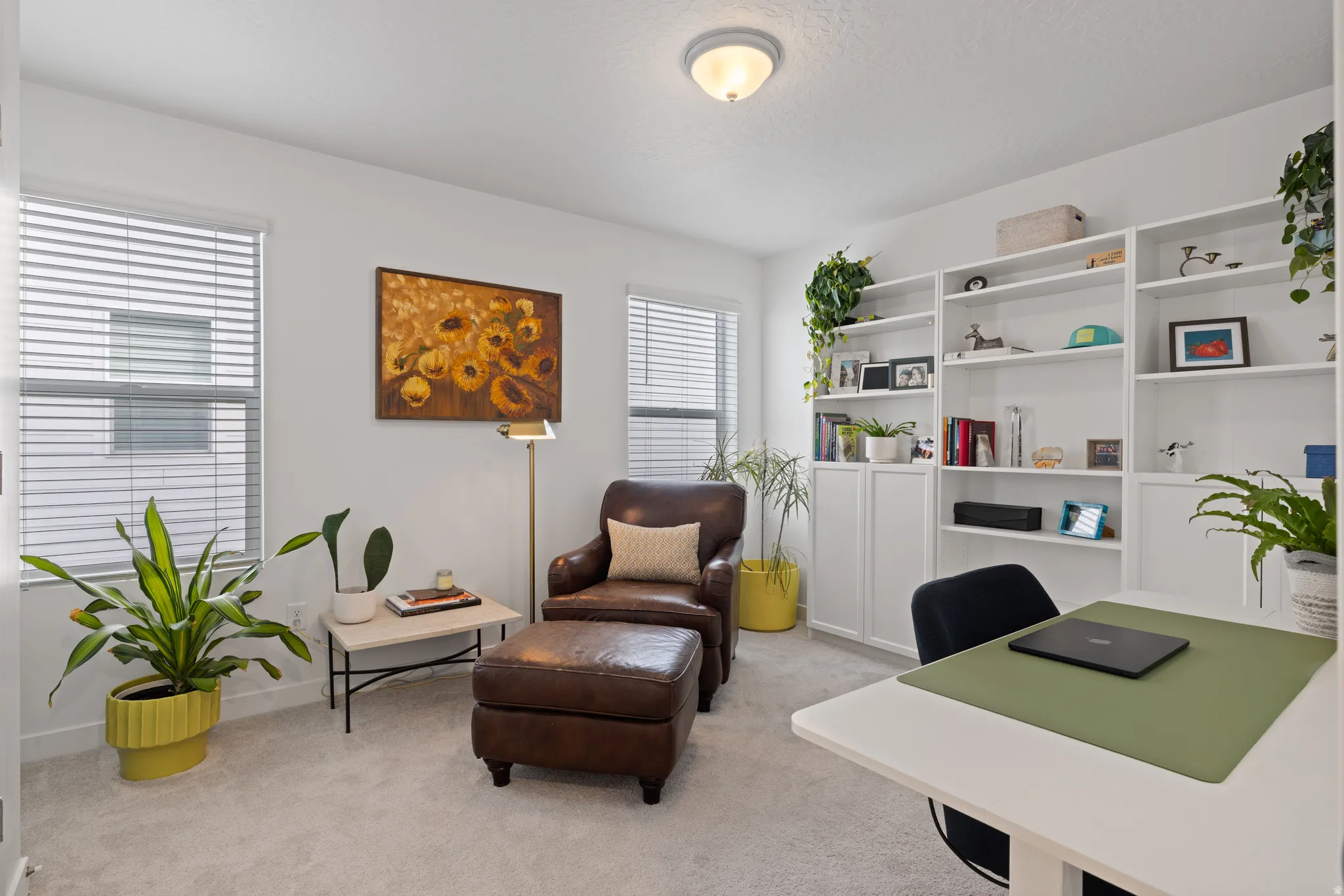 Bedroom 2 being used as a home office, featuring white walls, light carpet flooring, and two windows with horizontal blinds