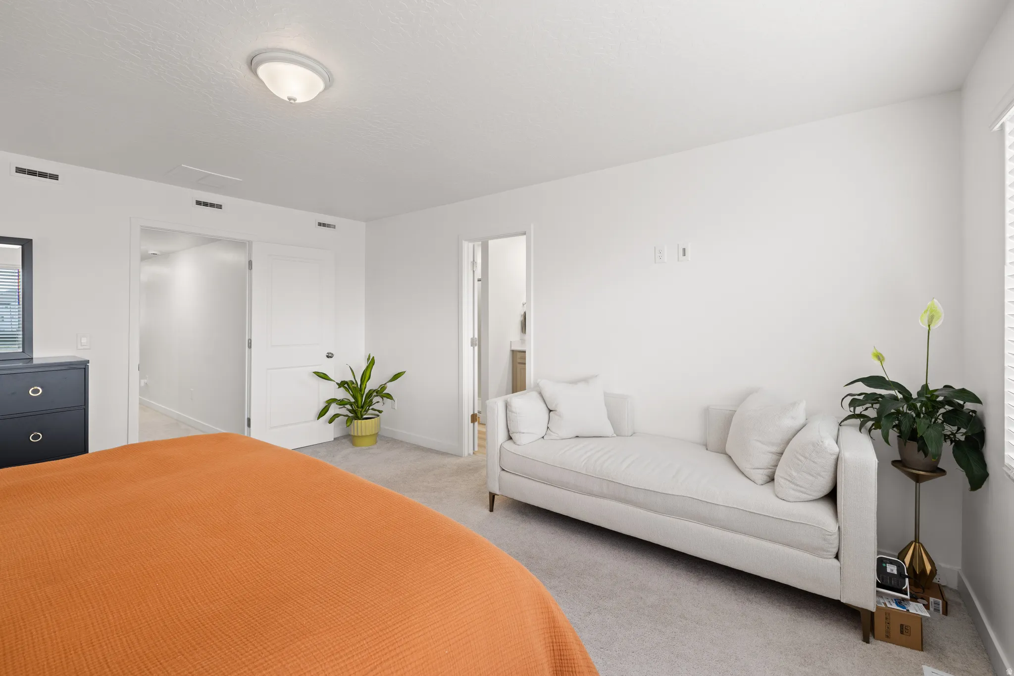 Spacious master bedroom featuring light-colored carpeting, white painted walls, and a semi-flush mount ceiling light fixture