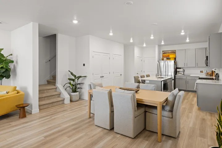 Open-concept living space featuring wood-finish flooring, recessed lighting, and a modern kitchen with grey cabinetry and stainless steel appliances