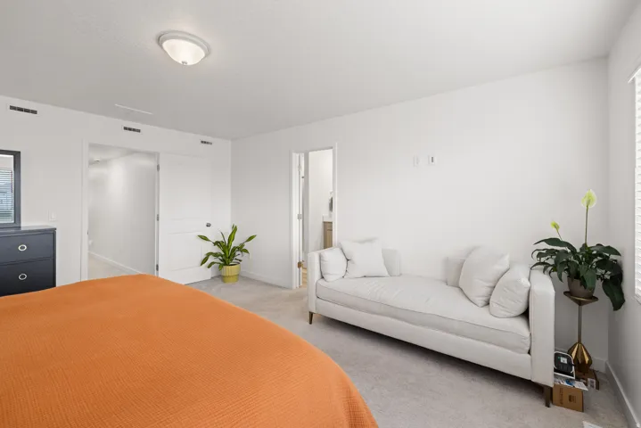 Spacious master bedroom featuring light-colored carpeting, white painted walls, and a semi-flush mount ceiling light fixture
