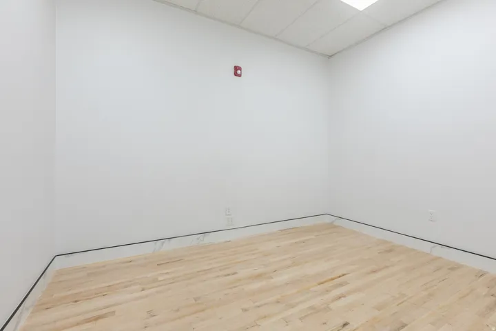 Bright room with light wood-finish flooring, white walls, and a drop ceiling with integrated lighting