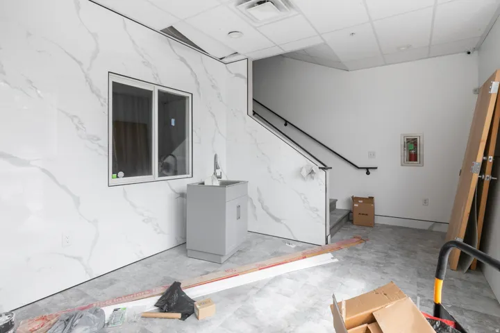 White marble-look wall paneling, a single window, and a gray vanity with an integrated sink