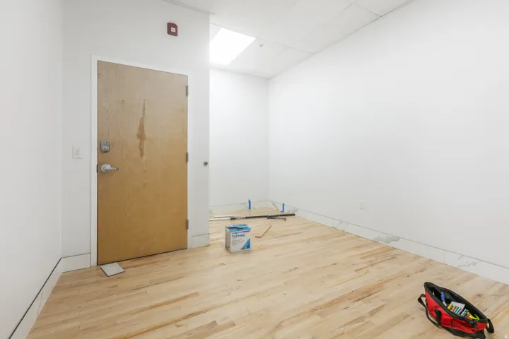 Light wood-finish flooring with white baseboards and neutral white walls