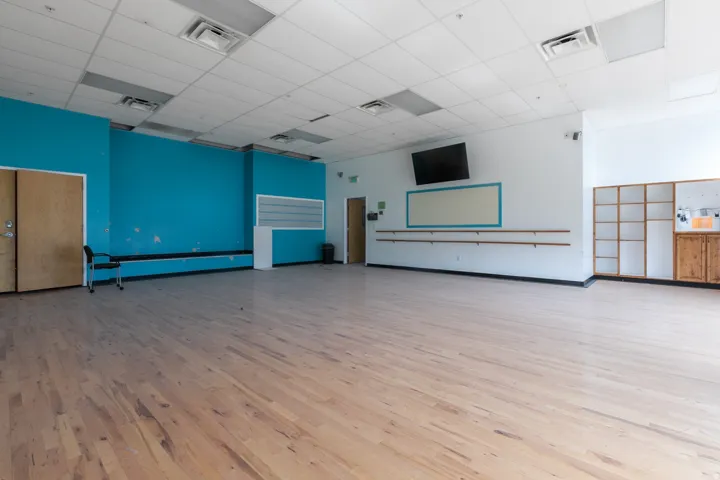 Spacious interior featuring wood-finish flooring and a drop ceiling with recessed lighting