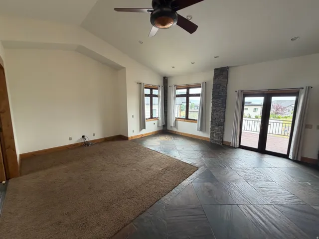 Spacious room featuring vaulted ceilings, a ceiling fan, and mixed flooring with both carpet and large format tile
