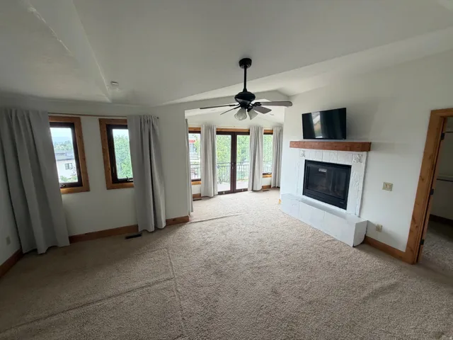 Spacious room featuring vaulted ceilings, a ceiling fan, and a built-in fireplace with a hearth and wood mantel