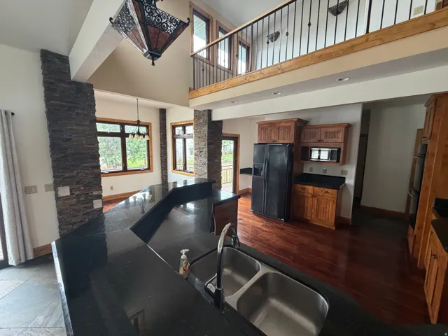 Kitchen island featuring a dual basin sink and dark countertops