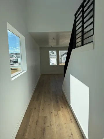 Entryway featuring wood-finish flooring, white walls, and a modern black metal staircase railing