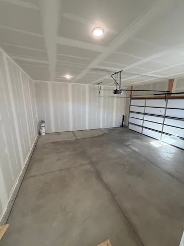 Spacious garage featuring a concrete floor, drywall-finished walls, and ceiling-mounted flush lighting