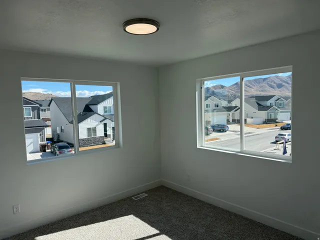 Bright interior space featuring two large windows, white walls, and a textured carpeted floor