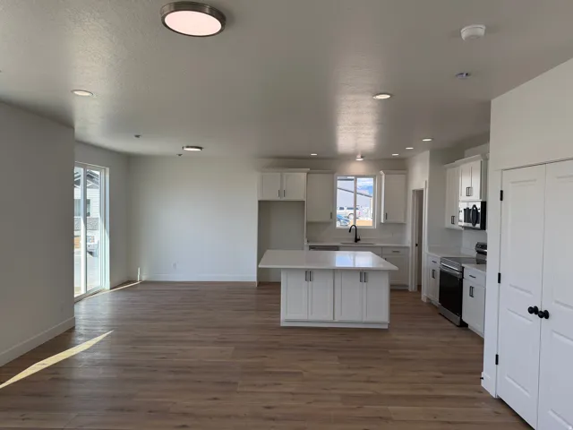 Modern kitchen featuring white shaker cabinetry, an island with countertop, stainless steel appliances, a black faucet, and recessed lighting