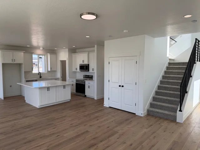 Modern kitchen with white shaker cabinetry, stainless steel appliances, and a central island with a solid surface countertop