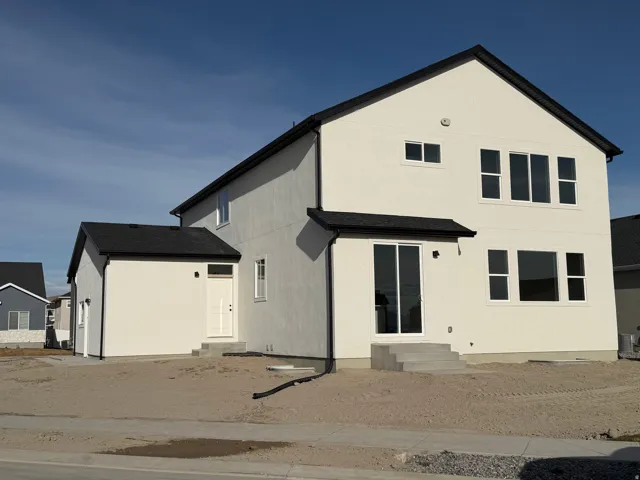Contemporary exterior featuring white stucco siding and a dark shingle roof