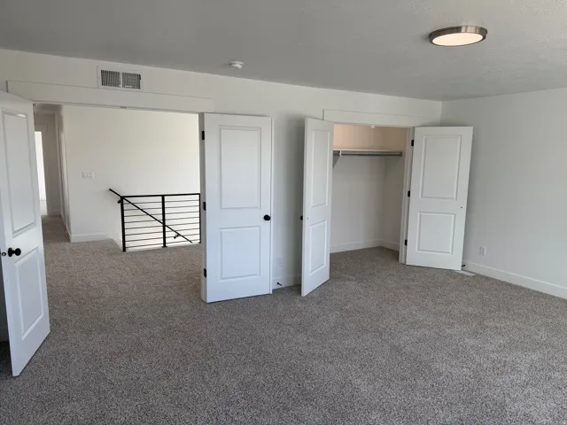 Carpeted room featuring white walls, a built-in closet with bi-fold doors, and an overhead flush-mount light fixture